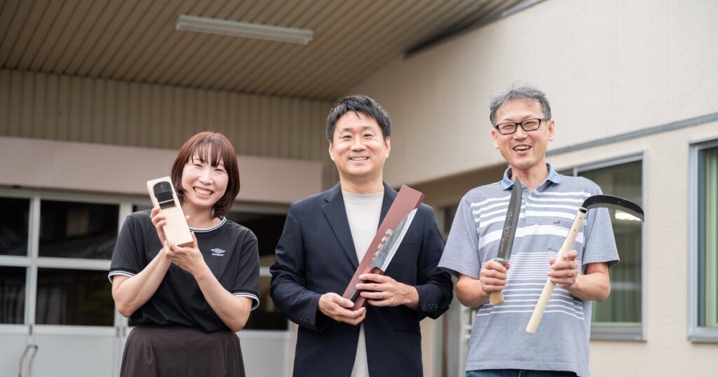 株式会社マルキンの小林宏聡専務、碁盤裕之室長、スタッフが刃物を手に並ぶ様子
