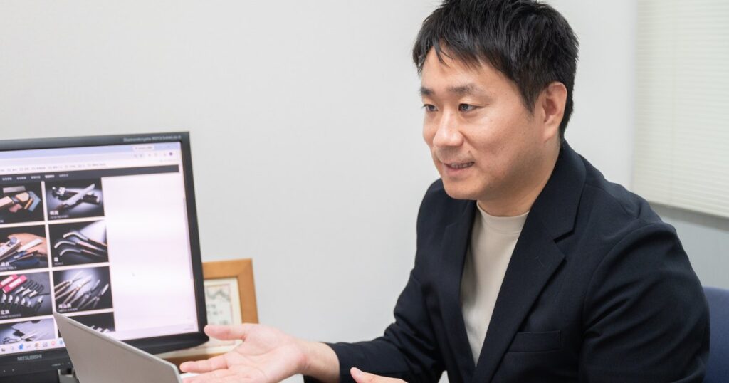 パソコンの商品ページを示しながらインターネット販売について話す小林宏聡さん