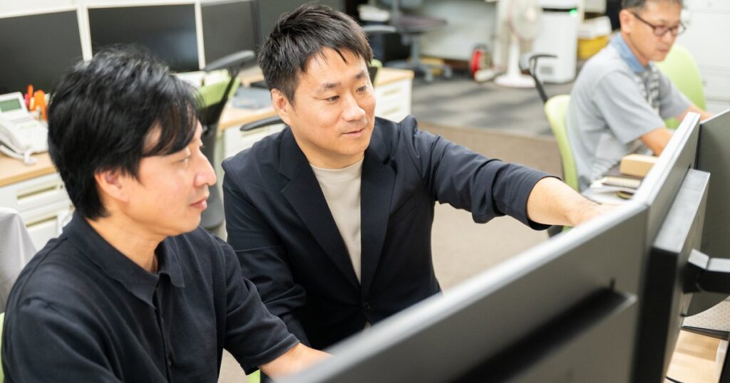 モニターを見ながら商品ページの打ち合わせをする小林宏聡さんとスタッフ